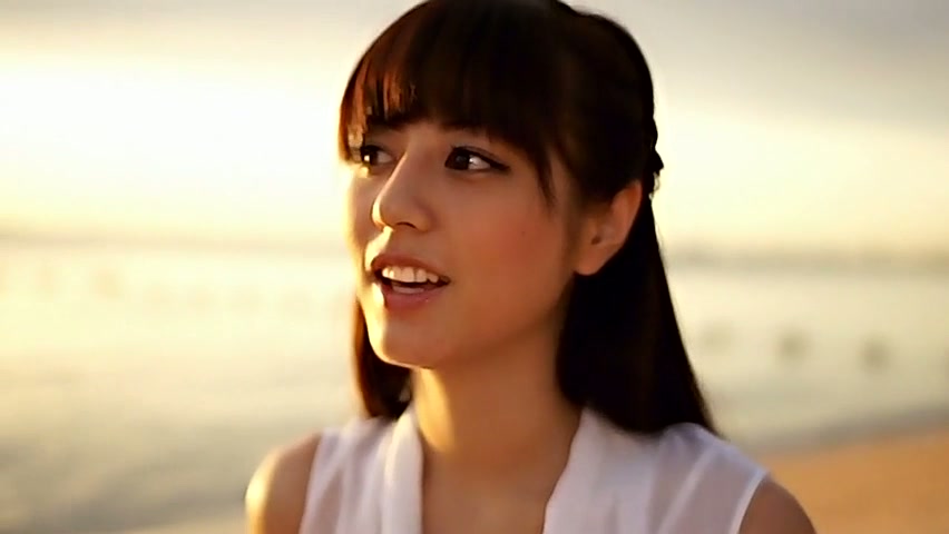 Magra ragazza Asiatica Yumi Sugimoto passeggiate su una spiaggia, indossando abito bianco